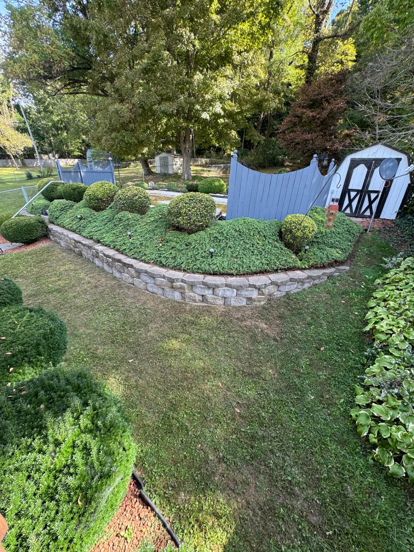 Long curved stone retaining wall wrapping a shrub bed