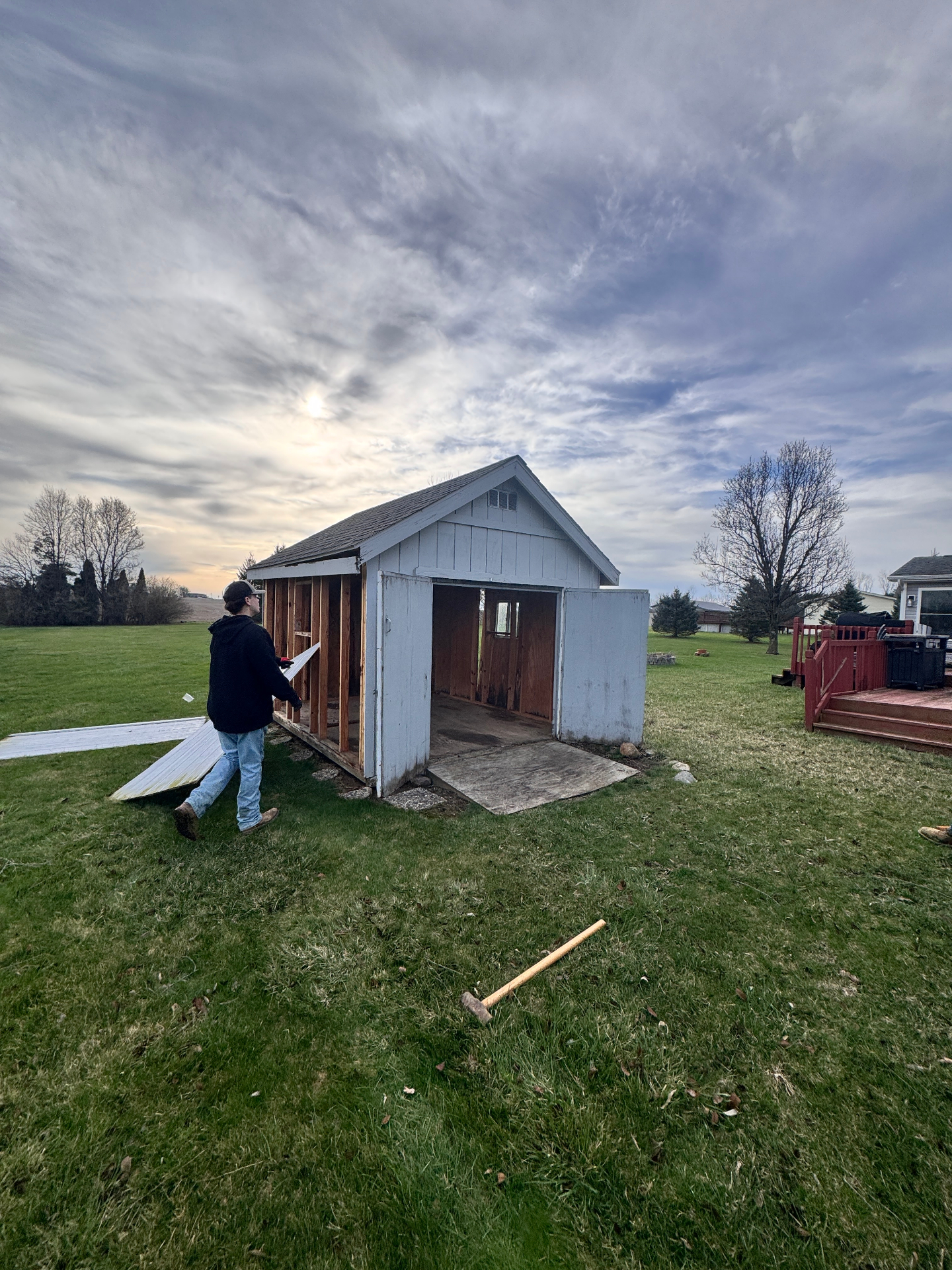 Partially dismantled white shed before demolition